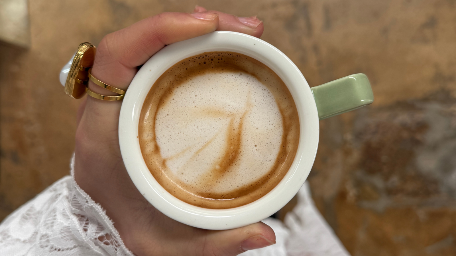 Person holding a coffee cup with latte.