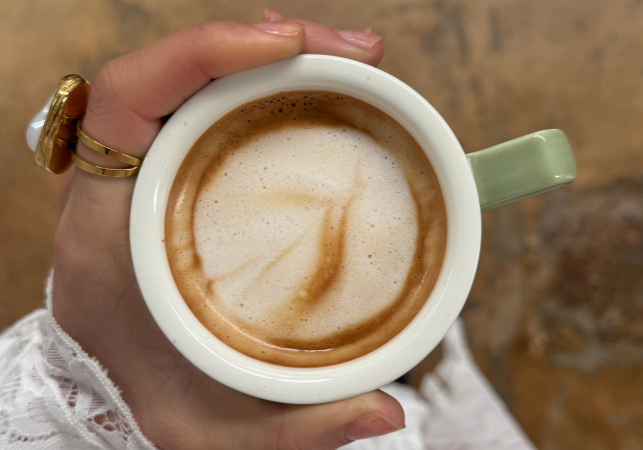 Person holding a latte coffee cup.